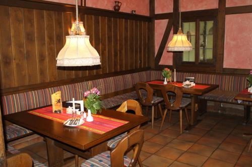 a restaurant with wooden tables and chairs and pendant lights at Hotel-Restaurant Stern in Geiselwind