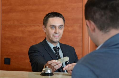 a man sitting at a table in front of a mirror at Hotel Neboder in Rijeka