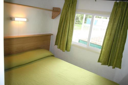 a small bedroom with a bed and a window at Bungalows Conca De Ter in Vilallonga de Ter