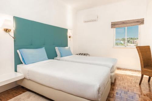 a hotel room with two beds and a window at Vila Channa - Adults Only in Albufeira
