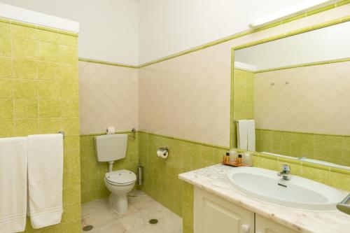 uma casa de banho com um lavatório, um WC e um espelho. em Vila Channa - Adults Only em Albufeira