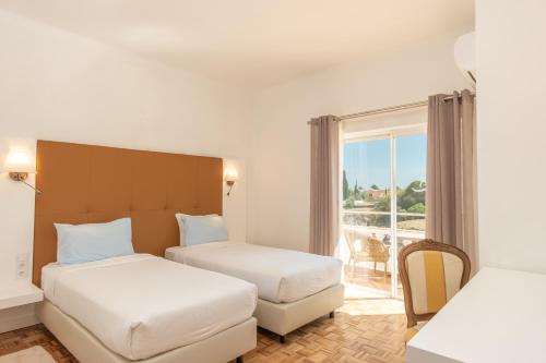 a hotel room with two beds and a balcony at Vila Channa - Adults Only in Albufeira