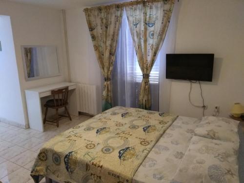 a bedroom with a bed and a desk and a television at Apartments Vitae in Pula