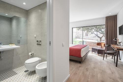 - une salle de bains avec toilettes et un lit dans une chambre dans l'établissement Caléway Hotel, à Vila Nova de Gaia
