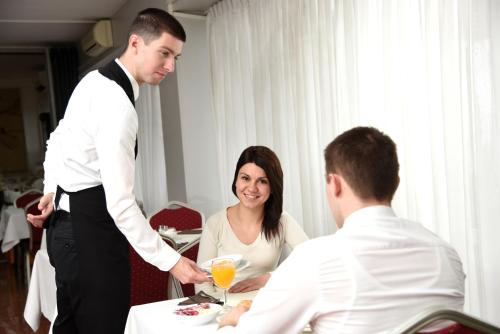 a man handing a woman a plate of food at Hotel Neboder in Rijeka