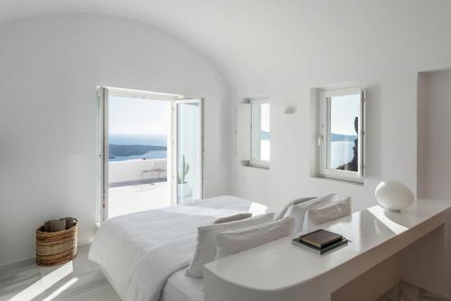 a white bedroom with a white bed and a window at White Ark in Fira