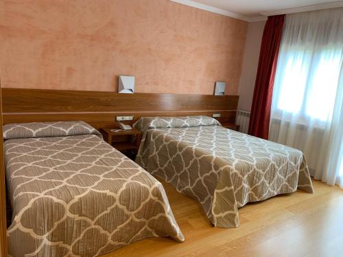 a hotel room with two beds and a window at Hotel Los Nogales in Campo