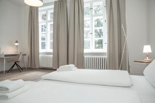 a bedroom with two beds and a desk and windows at Boardinghouse Flensburg - by Zimmer FREI! Holidays in Flensburg