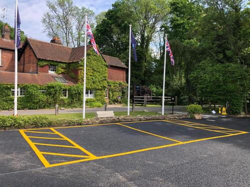 a parking lot with flags in front of a building at Trivelles Waterhall Country Gatwick Hotel & airport parking in Crawley