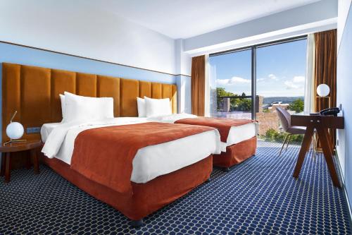 提比里斯的住宿－Zemeli Boutique Hotel by DNT Group，酒店客房设有两张床、一张书桌和一个窗户。