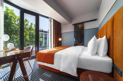a hotel room with a bed and a desk and window at Zemeli Boutique Hotel by DNT Group in Tbilisi City
