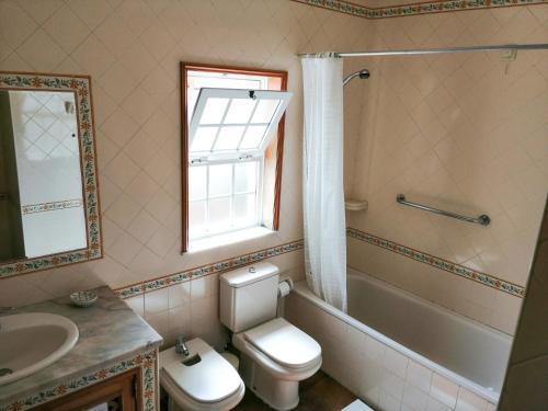 a bathroom with a toilet and a sink and a window at Casa da Balseira in Aveiro