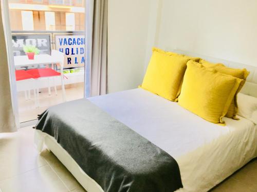 a bedroom with a bed with yellow pillows and a window at Céntrico Apartamento con Balcón cerca de la Playa in Puerto de la Cruz