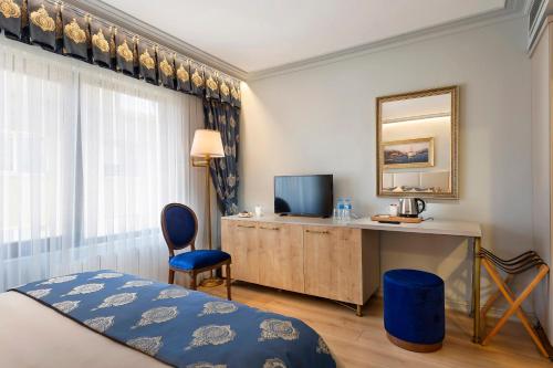 Habitación de hotel con cama, escritorio y TV. en Güner Business Hotel, en Estambul
