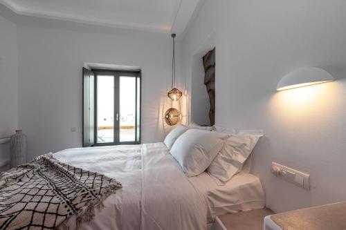 a white bedroom with a large bed with a window at Bohemian Luxury Boutique Hotel, Adults Only in Naousa