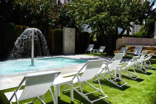 a row of lawn chairs in front of a fountain at Apartamentos La Era Park in Benidorm
