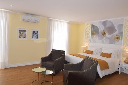 a hotel room with a bed and two chairs at Lx Flowers Apartments in Lisbon