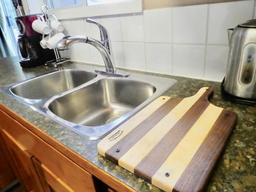 a kitchen counter with a sink and a cutting board at Belle Neige Suites: Whistler in Whistler