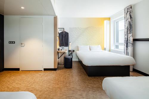 a hotel room with two beds and a desk at B&B HOTEL Cergy Saint Christophe in Cergy