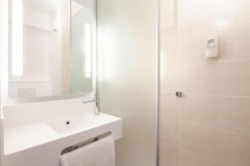 a white bathroom with a sink and a mirror at B&B HOTEL Cergy Saint Christophe in Cergy