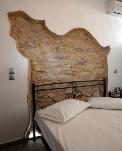 a bed in a room with a stone wall at Margarita's Rooms in Chora Folegandros