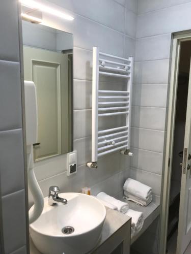 La salle de bains blanche est pourvue d'un lavabo et d'un miroir. dans l'établissement Moonlight Hotel, à Chişinău