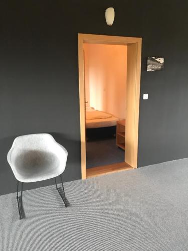 a white chair in a room with a bedroom at Gästehaus & Café Leeze in Bad Dürkheim