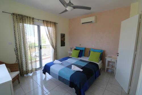 Un dormitorio con una cama con almohadas azules y verdes. en The Paradise Townhouses By Taimoura, en Pafos
