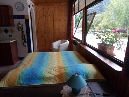 a bedroom with a bed with a colorful blanket and a window at Chalet del Laghetto in Chiusa di Pesio