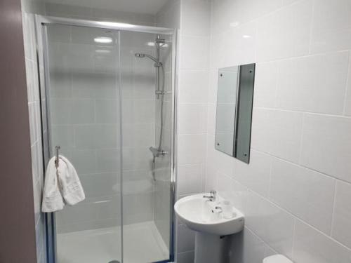 a white bathroom with a shower and a sink at The Avenue Club and Lodge in Birmingham
