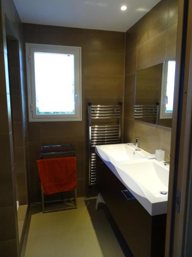 a bathroom with a white sink and a red chair at Résidence Coté Plage in Sainte-Lucie de Porto-Vecchio