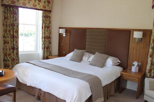 a hotel room with a large bed with white sheets at Mackays Hotel in Wick