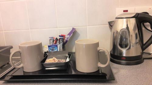 two coffee mugs on a stove with a tea kettle at Mackays Hotel in Wick