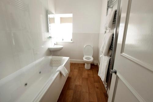 a white bathroom with a tub and a toilet at Mackays Hotel in Wick