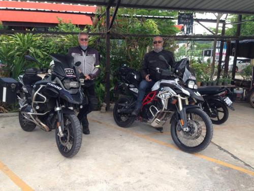 two men sitting on motorcycles in a parking lot at Banana Resort Sadao in Sadao