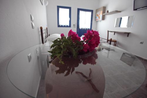a glass table with a vase with flowers on it at Margarita's Rooms in Chora Folegandros