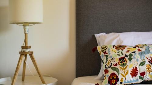 a lamp sitting on a table next to a pillow at Pine House - Faro Airport, Beach and City Center in Faro