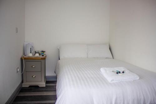 a small bedroom with a white bed and a night stand at Crofts Hotel in Cardiff