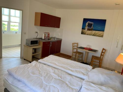 a bedroom with a white bed and a kitchen at Studio "MS Muschel" im Ferienpark in Neddesitz