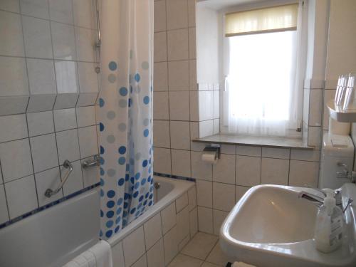 een badkamer met een wastafel, een bad en een raam bij Pension am Lieserpfad in Manderscheid