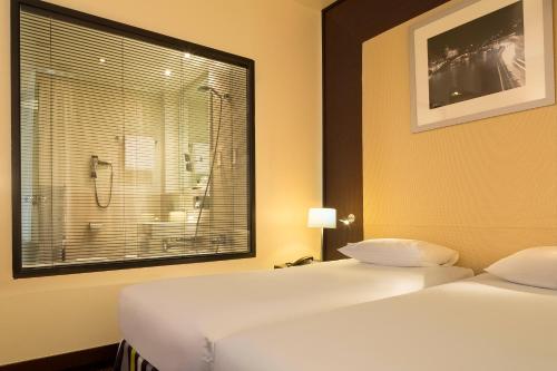 a bedroom with two beds and a window with a shower at Hôtel Le M in Paris