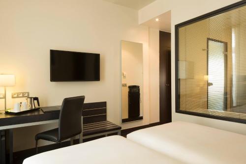 a hotel room with a desk and a tv on the wall at Hôtel Le M in Paris