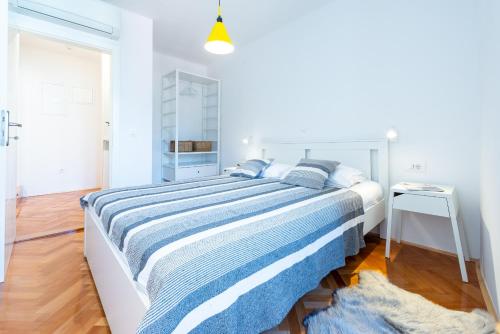 een witte slaapkamer met een groot bed met blauwe lakens bij Apartments Simović Old Town in Dubrovnik