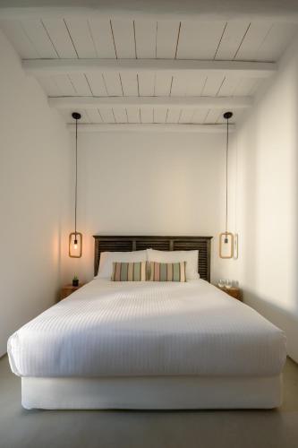 a bedroom with a large white bed with two lamps at The Summit of Mykonos in Kalo Livadi