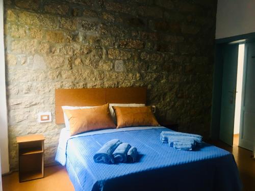 a bedroom with a blue bed with a stone wall at La Vecchia Posta B&B in Calangianus