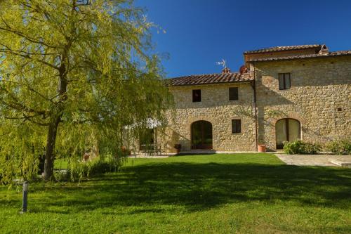 a large stone house with a tree in the yard at Cavarchino B&B in Gaiole in Chianti