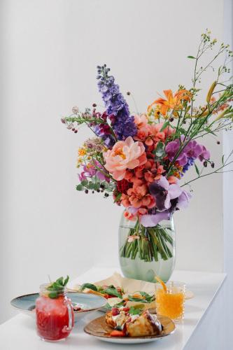 a vase filled with flowers next to a plate of food at Gorki Apartments in Berlin