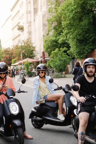 two people riding on a scooter on a city street at Gorki Apartments in Berlin