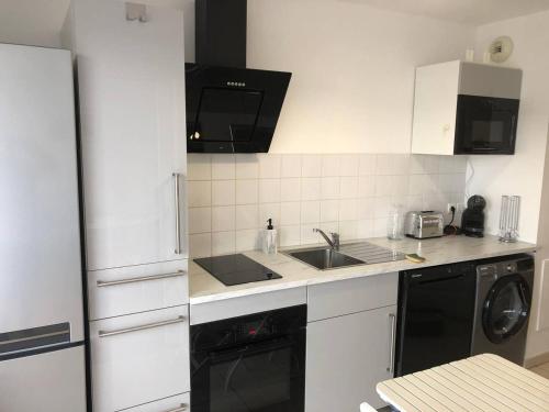 une cuisine blanche avec un évier et un lave-vaisselle dans l'établissement ARCACHON appartement T2 51M2 et parking privatif en sous sol, à Arcachon