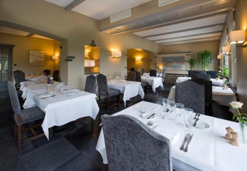 a dining room with white tables and chairs at Hotel des Ardennes in Corbion